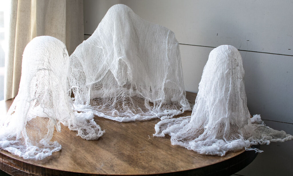 3 ghosts made with cheesecloth soaked in liquid fabric stiffener and allowed to dry.