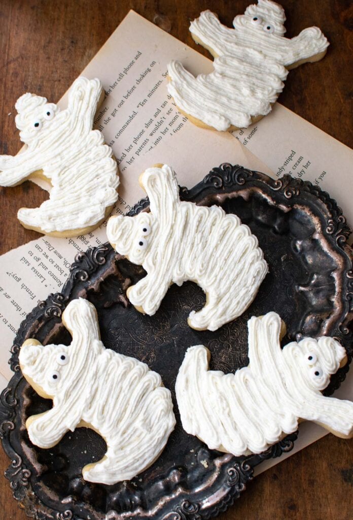 Shortbread cookies cut out into ghost shapes and decorated with white buttercream frosting.