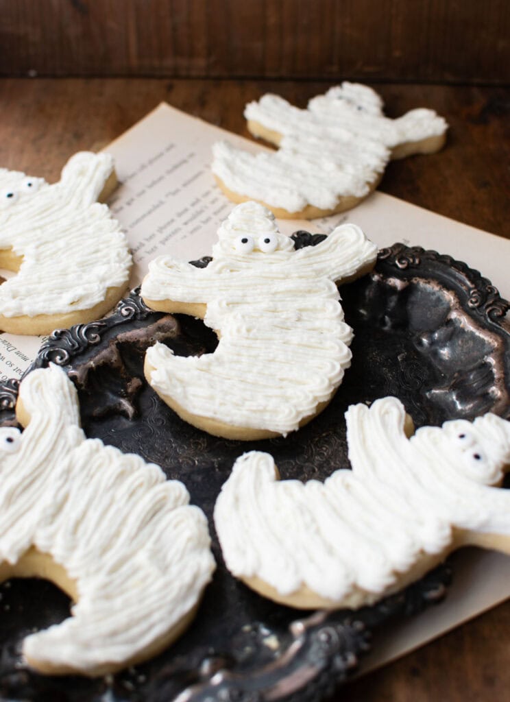 5 Frosting Halloween Ghost Cookies on a tarnished silver tray.