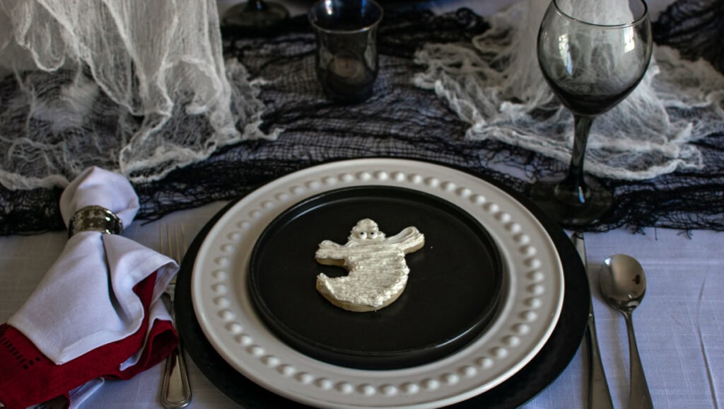 A place setting on a black and white ghost themed Halloween Tablescape.