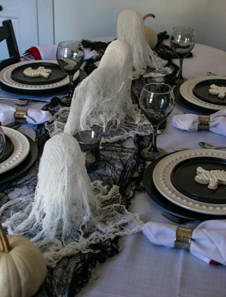 A table set for a Halloween Party with homemade cheesecloth ghosts down the centre.