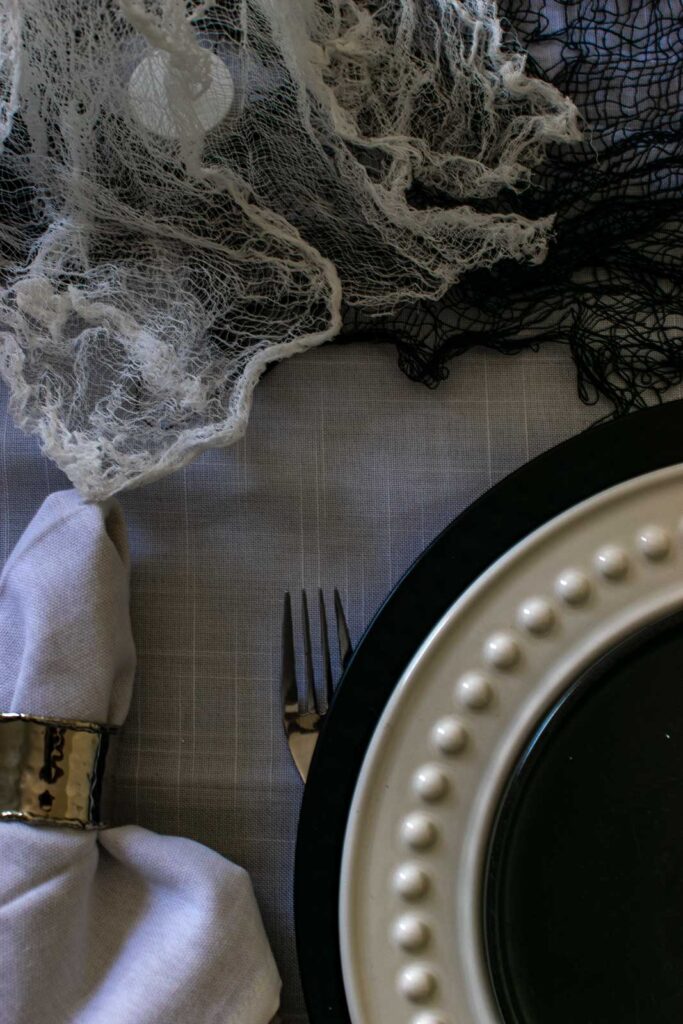 A close up of the edge of a plate stack that includes a black charger plate topped with a white dinner plate and a black salad plate.