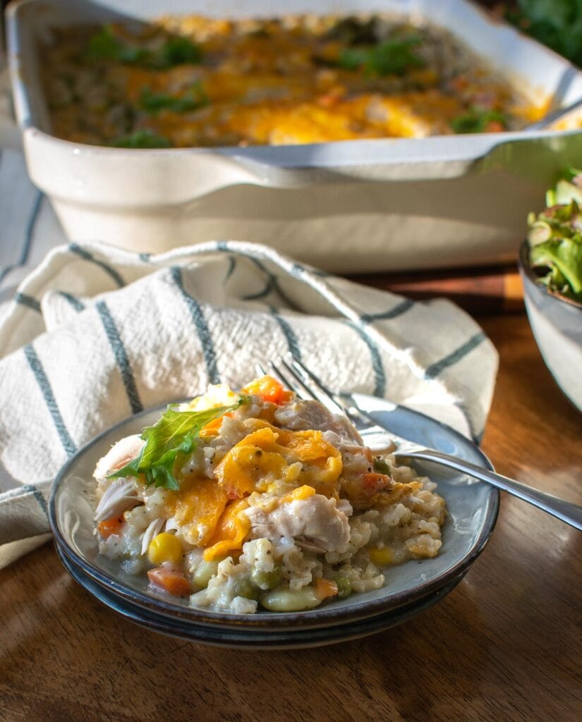 A plate of chicken, rice and veggie casserole topped with melted cheese.