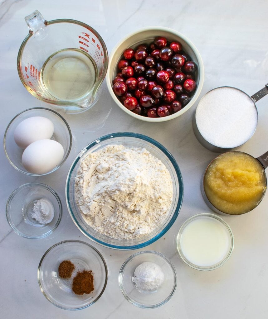 Ingredients to make Cranberry applesauce bread including flour, fresh cranberry, spices and eggs and applesauce.