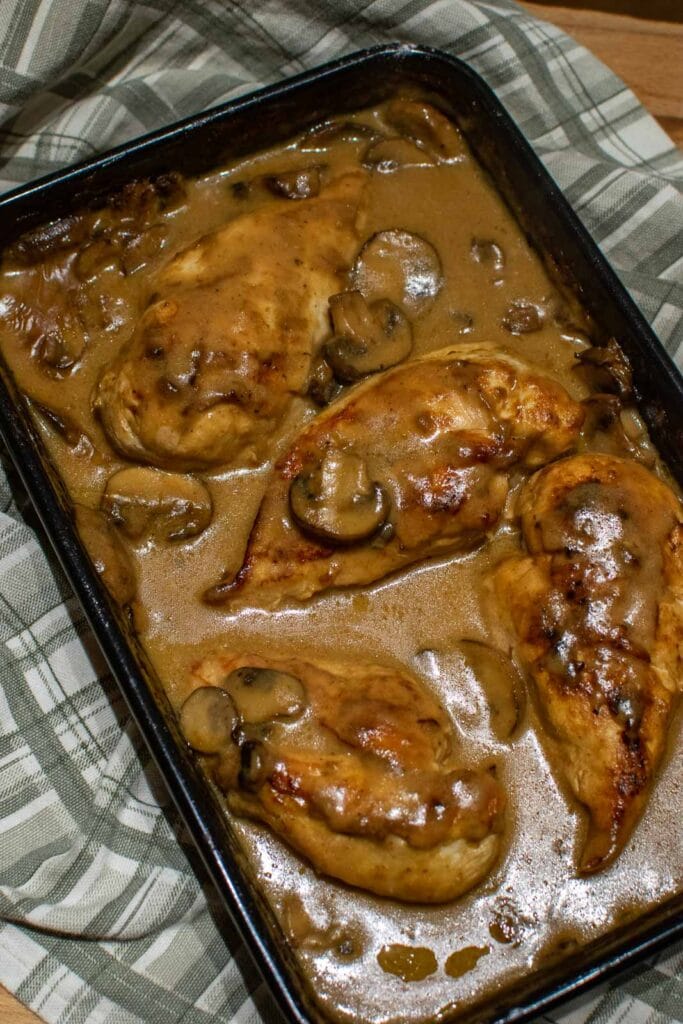 Chicken in a creamy mushroom and onion sauce in a baking pan fresh out of the oven.