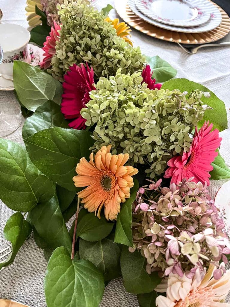 A centrepiece for a formal Thanksgiving dinner table made with greens, dried hydrangeas blossoms and Gerbera daisies.