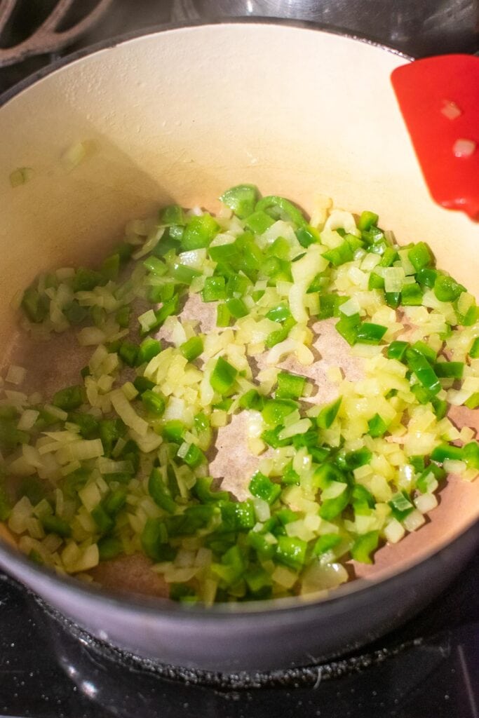 chopped onion and chopped green pepper cooking in olive oil in a dutch oven.