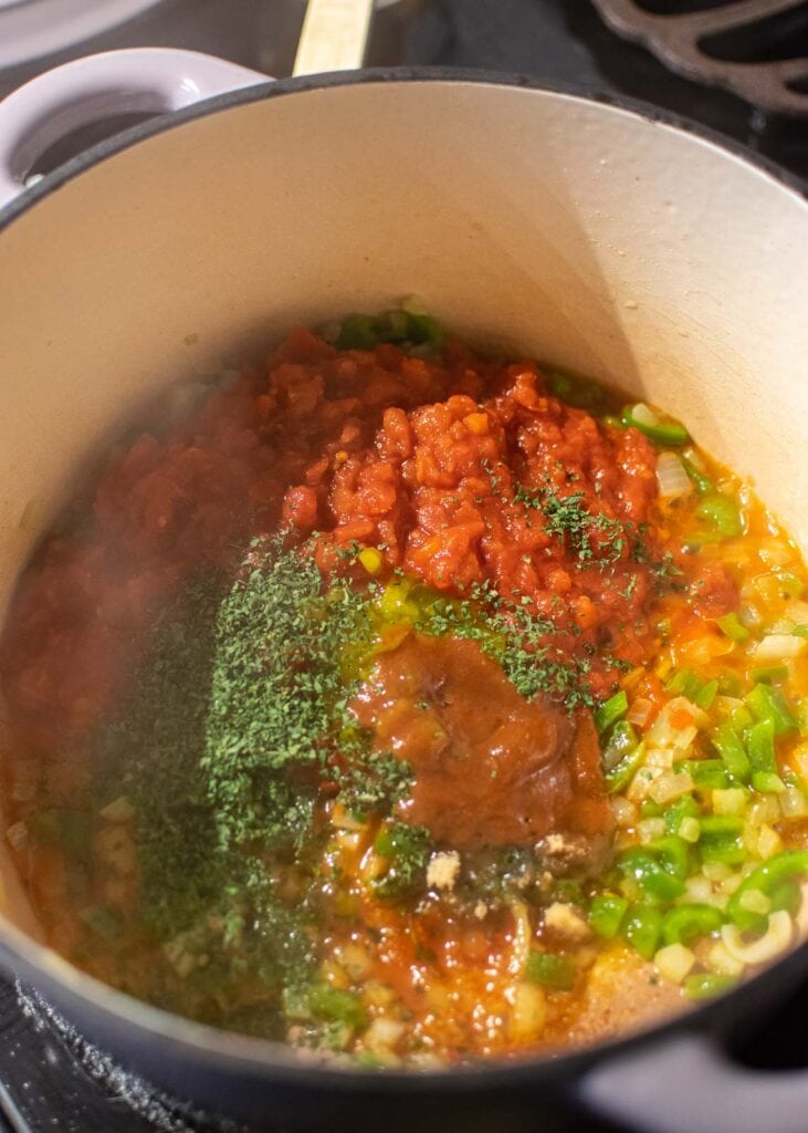 Tomatoes, corn, condiements and spices added to cooked onion and pepper mixture in a dutch oven.