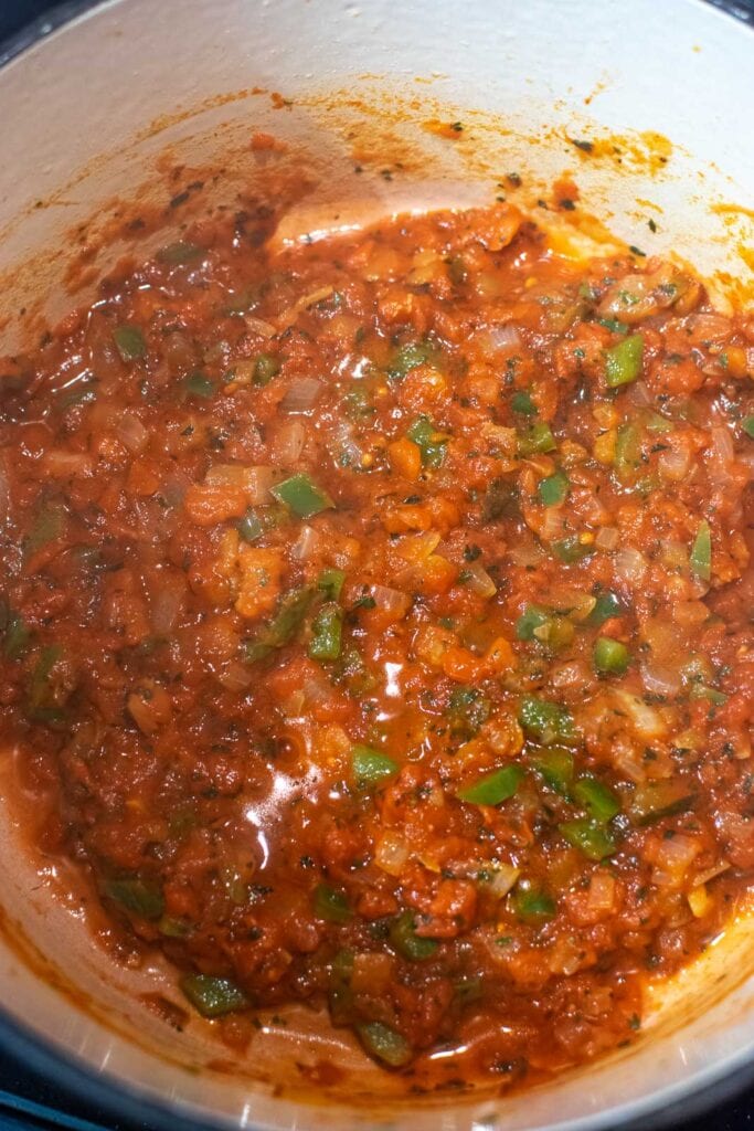 Tomato and onion base for lentil and bean stew, simmering on low heat in a dutch oven.