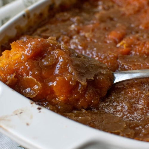 A scoop of brown sugar sweet potato casserole being lifted from the dish.