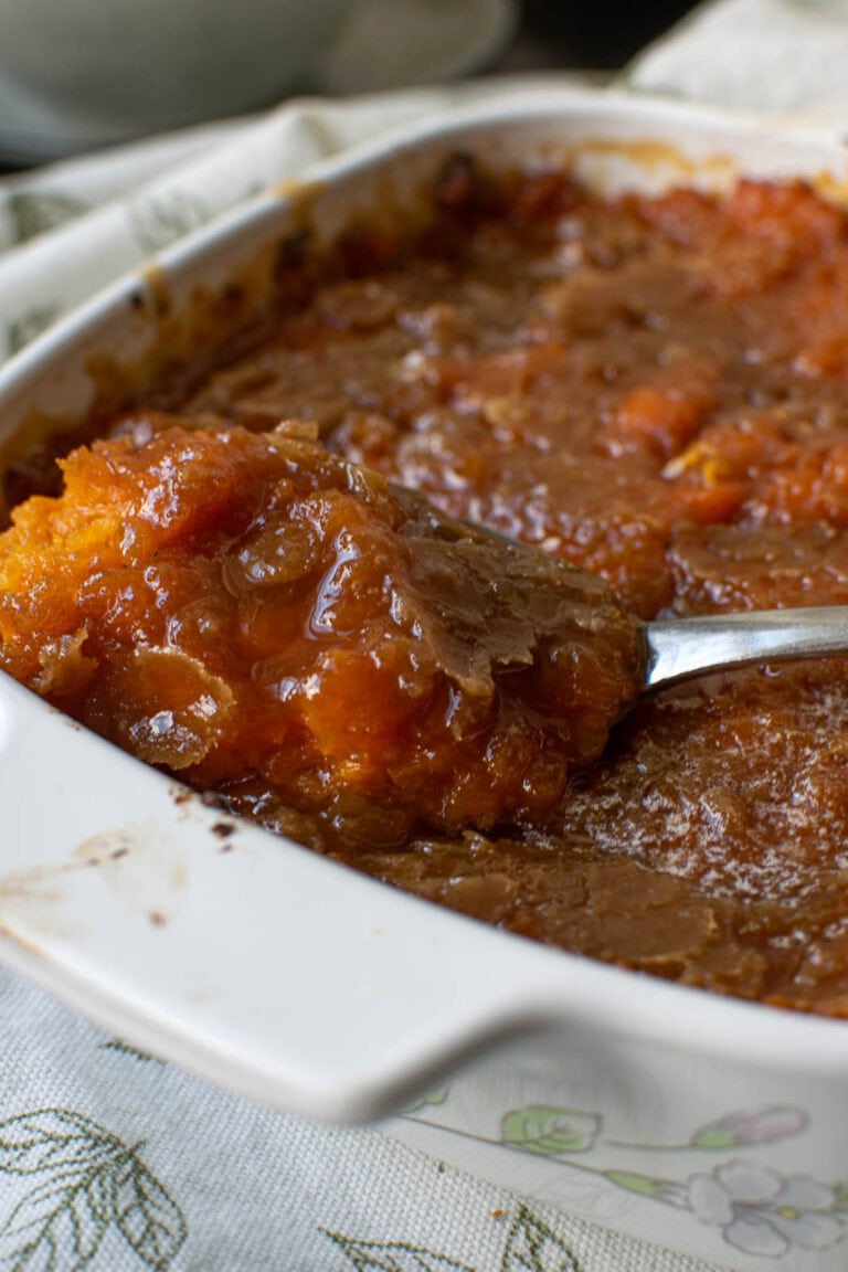 A scoop of brown sugar sweet potato casserole being lifted from the dish.
