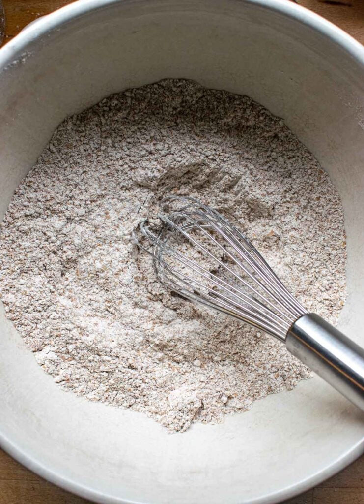 Dry ingredients to make mincemeat muffins including flour and bran whisked together in a large mixing bowl.