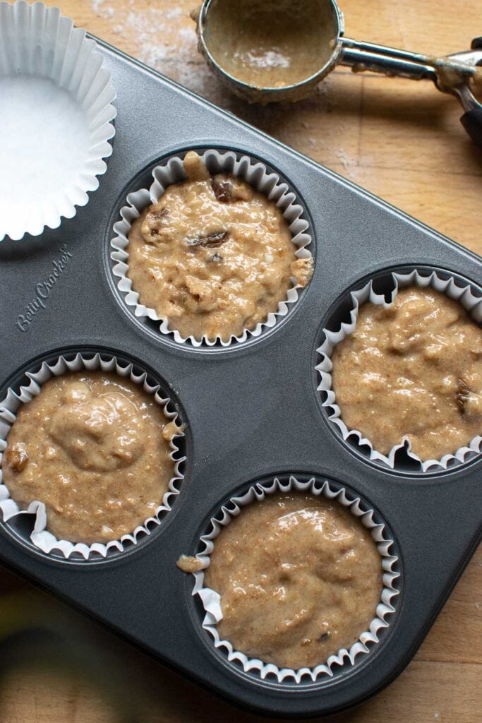 Mincemeat muffin batter poured into paper lined muffin tins before baking.