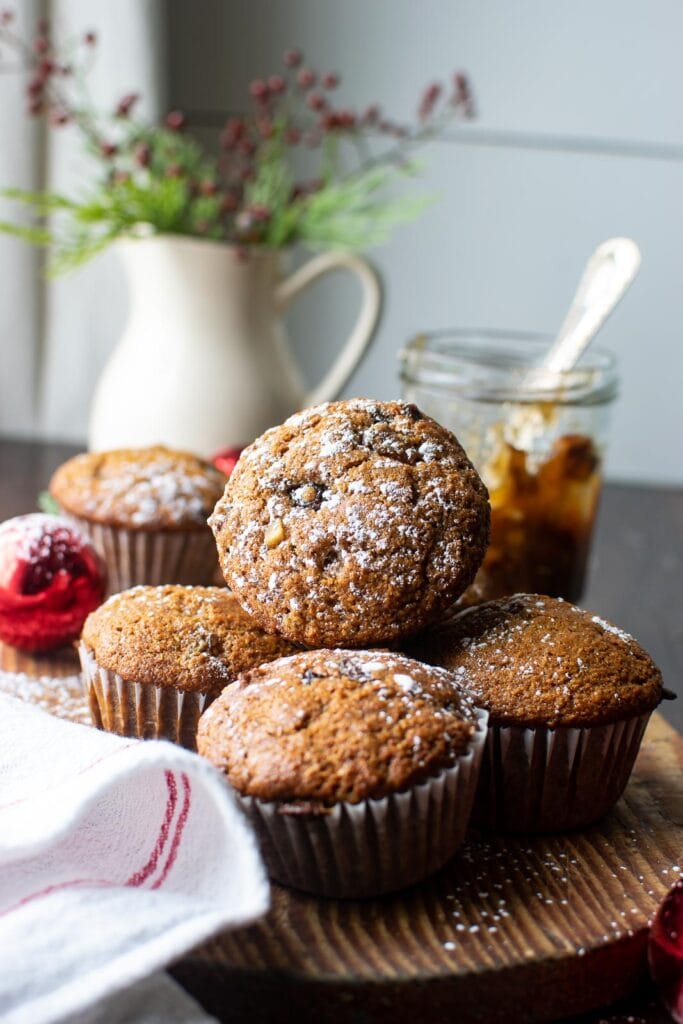 Muffins made with mincemeat are stacked on a cutting board and sprinkled with powdered sugar.