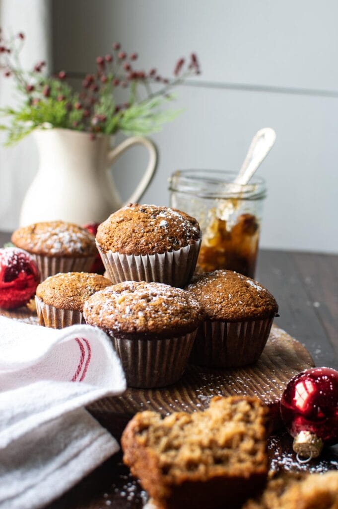 Mincemeat muffins stacked on a cutting board with a half empty jar of mincemeat in the background.