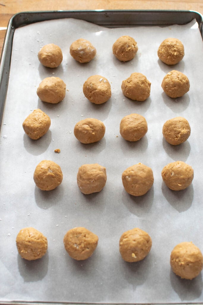 Peanut butter balls on a parchment lined baking tray before being coated with chocolate.