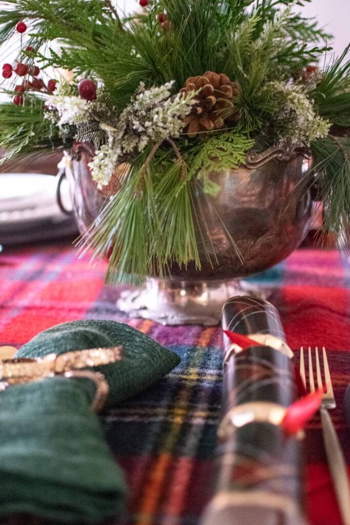 A Christmas centrepiece in an antique silver trophy bowl filled with fresh pine and cedar branches, and red berries.