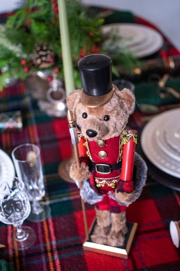 A teddy bear nutcracker on a Christmas dinner table.