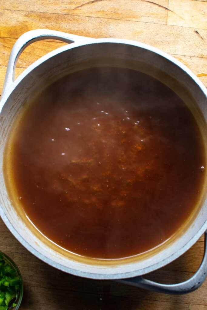 Thickened sweet and sour sauce in a frying pan before adding pineapple, green pepper and meatballs.