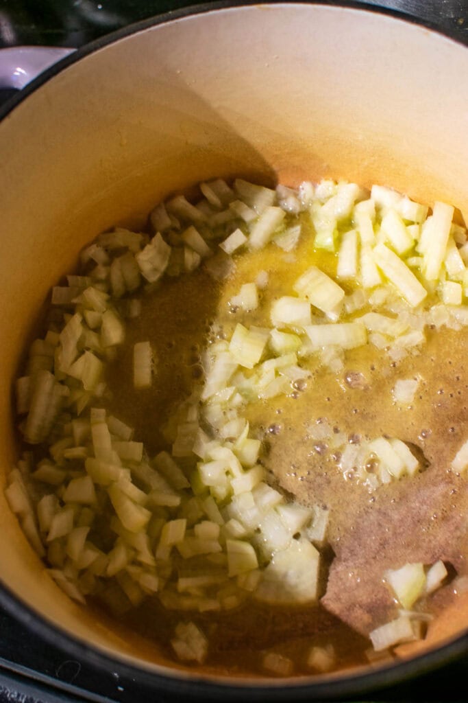 Chopped onions cooking in melted butter in a dutch oven pot.