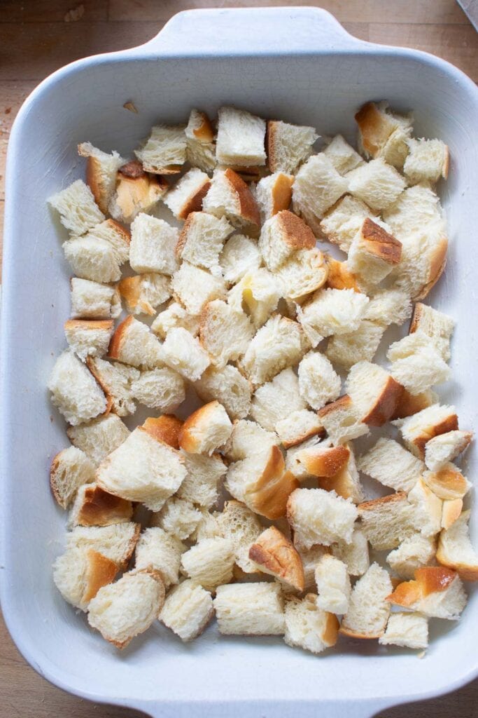 Cubed bread in the bottom of a buttered casserole dish.
