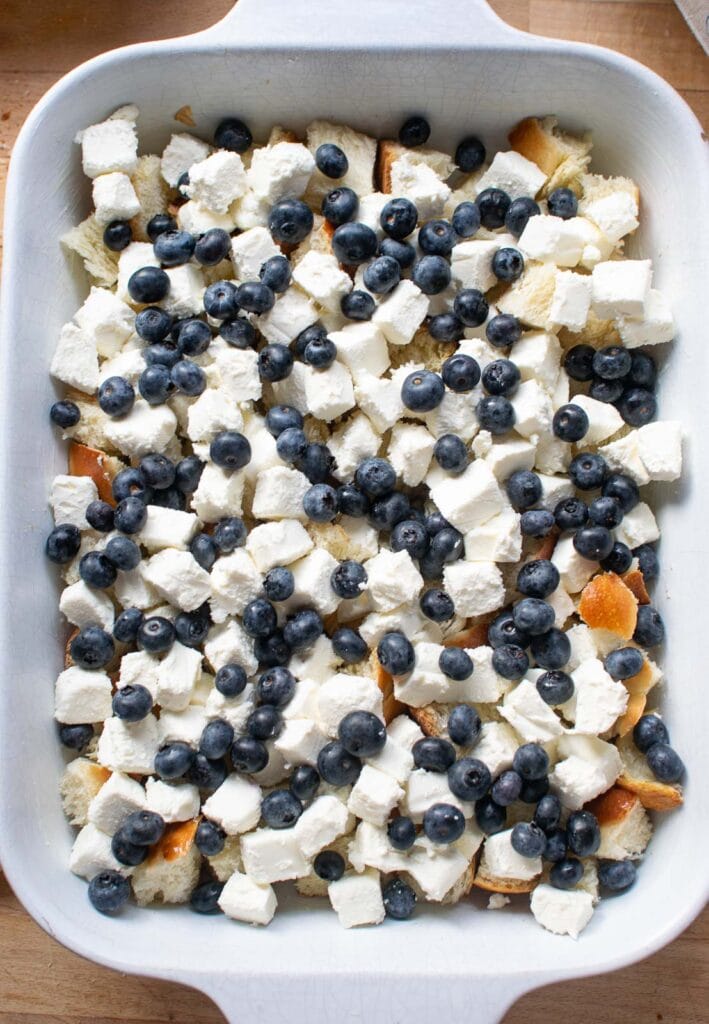 Blueberries sprinkled over cubed bread and cream cheese to make French Toast casserole.