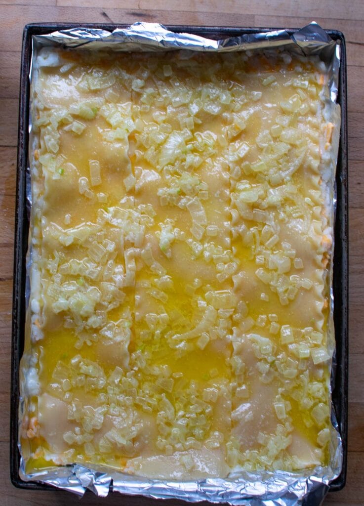 Melted butter and onions poured over top of third and final layer of lasagna noodles to make a perogy casserole.