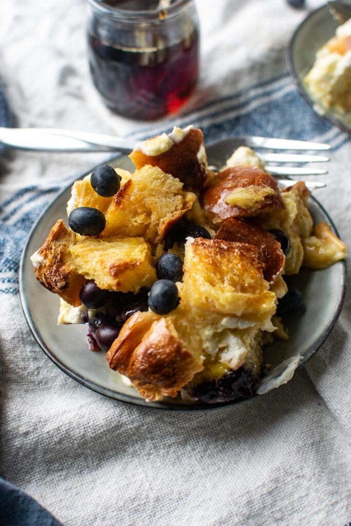 A plate of blueberry French toast casserole sprinkled with additional fresh blueberries.