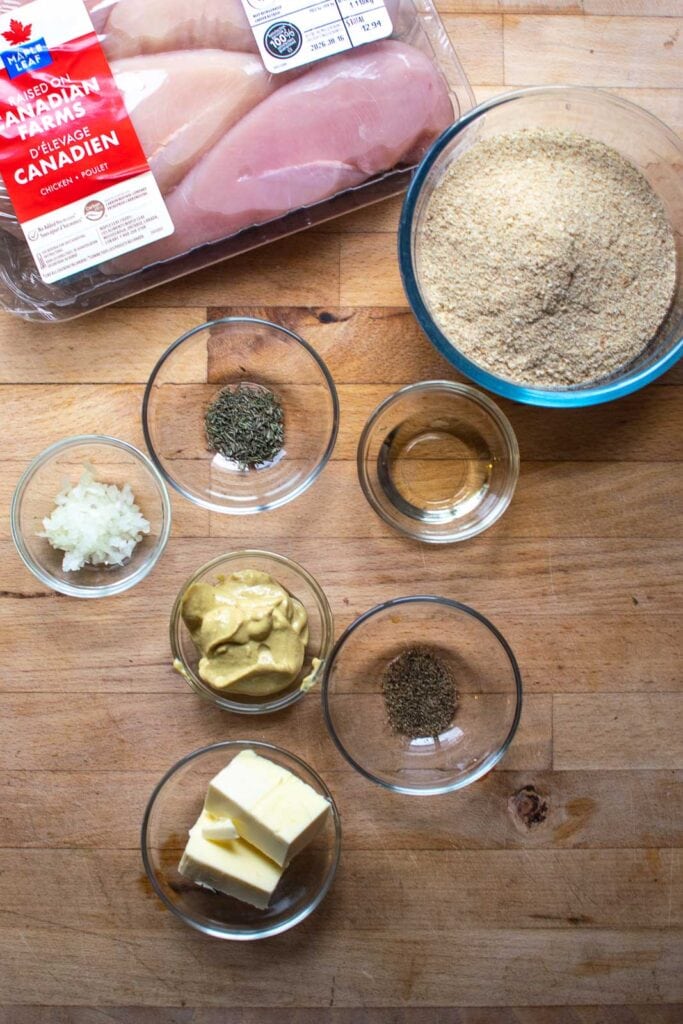 Ingredients to make crispy Dijon chicken including chicken breasts, butter, oil, thyme, black pepper, onions and bread crumbs.
