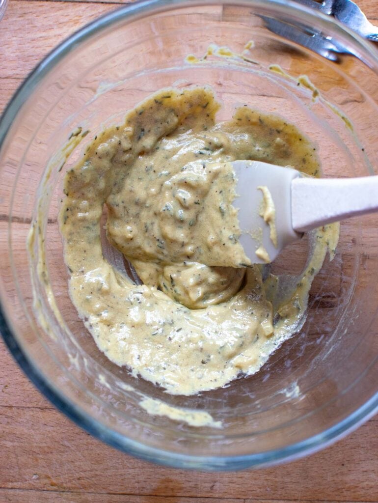 Finished Dijon sauce including Dijon mustard, spices, melted butter and oil all mixed together in a glass bowl.