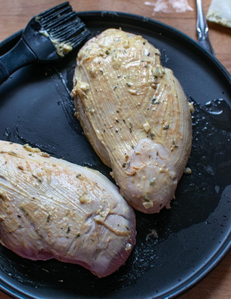 Browned chicken breast coated with a Dijon Mustard mixture on a black plate.