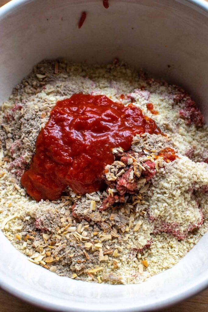 All the ingredients to make glazed meatloaf in a large mixing bowl, but not yet mixed together.