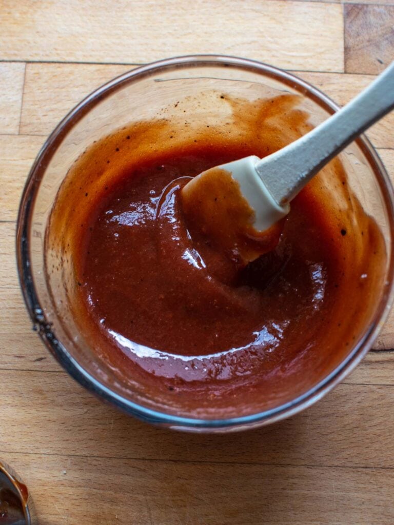 A small glass bowl with a ketchup based glaze for topping on meatloaf.
