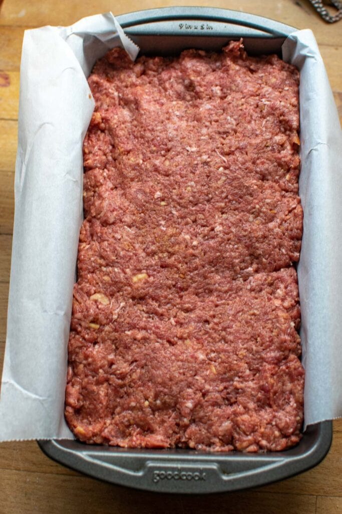 Uncooked meatloaf mixture pressed into a parchment lined loaf pan.