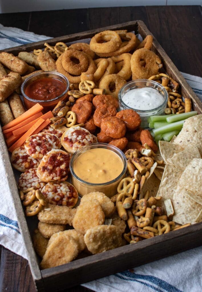 A snack board made for game day featuring all the foods found at a sports bar such as nachos, wings and pizza.