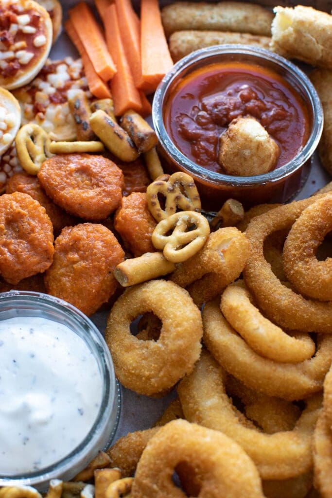 A large game day platter with onion rings, pretzels and vegan chicken wings.