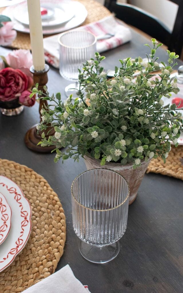 A Valentine's Day table setting with faux green plants and other natural elements.