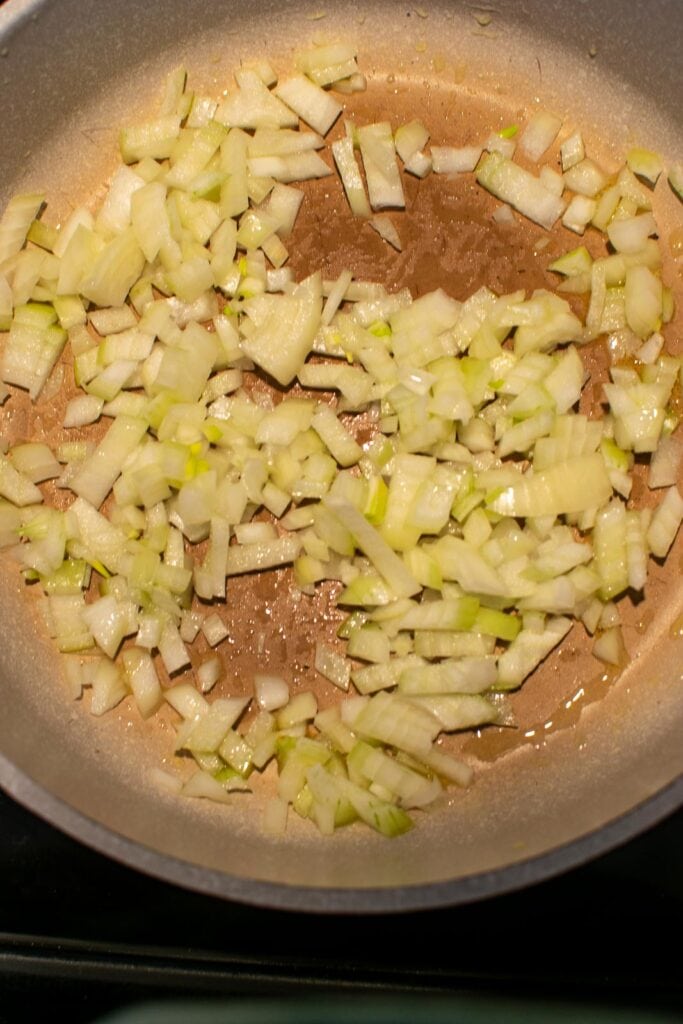 Chopped onions frying over low heat on the stove top.
