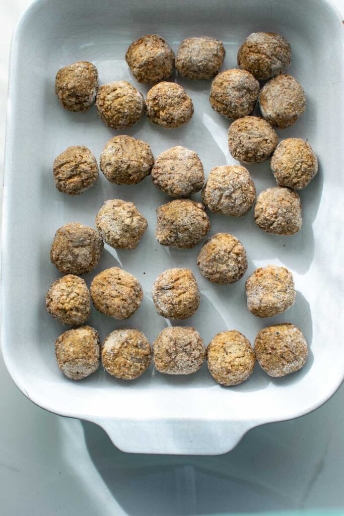 frozen meatballs arranged in a glass casserole dish.