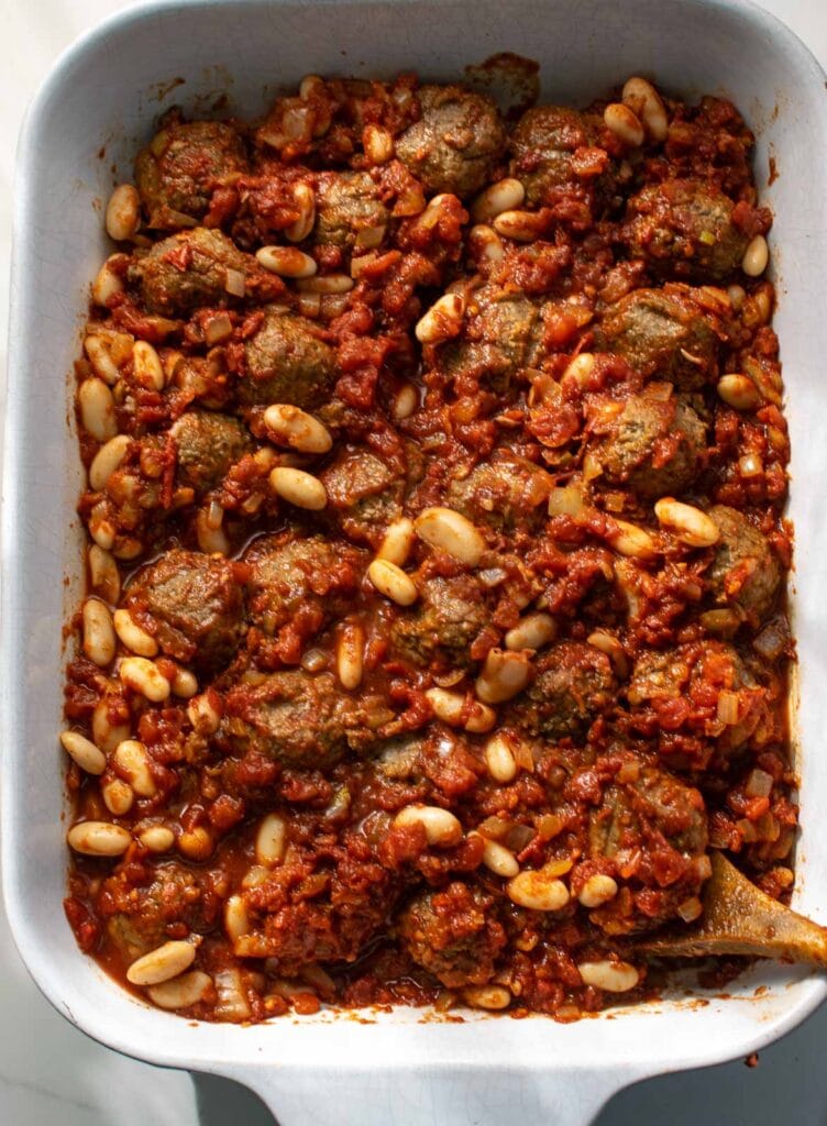 Frozen meatballs and kidney beans stirred into chili tomato mixture in a casserole dish.
