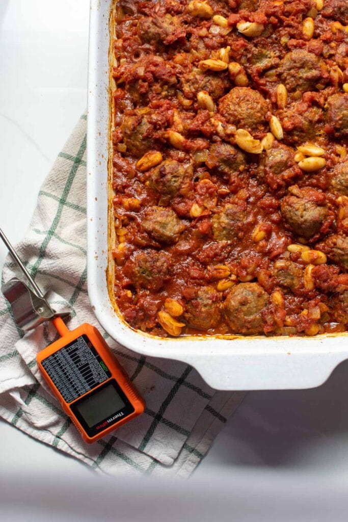 Meatball chili casserole fresh from the oven with a meat thermometer beside the casserole dish.