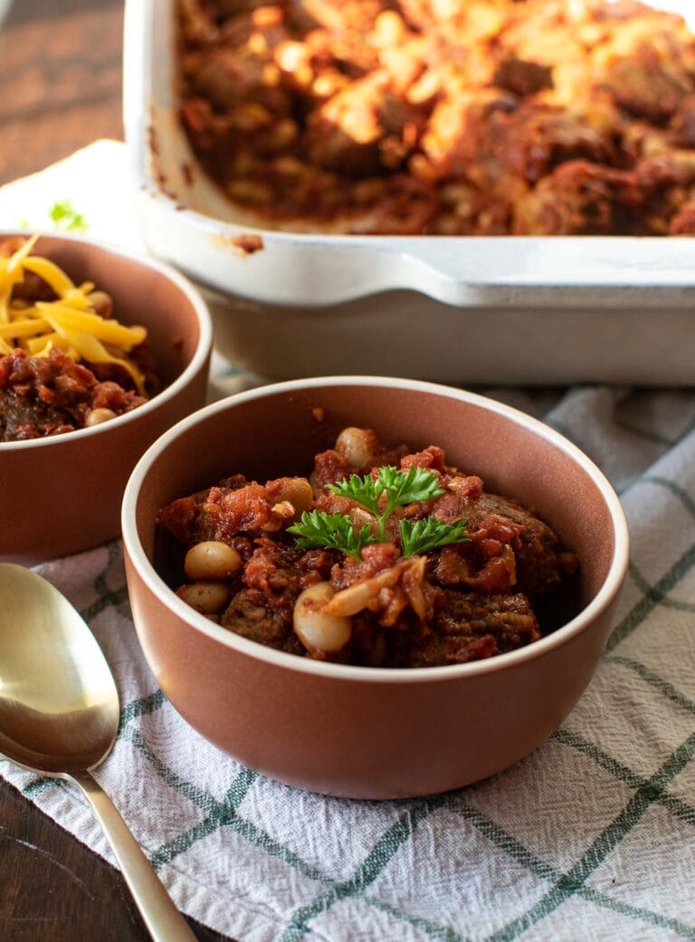 A bowl of meatball chili topped with fresh parsley.