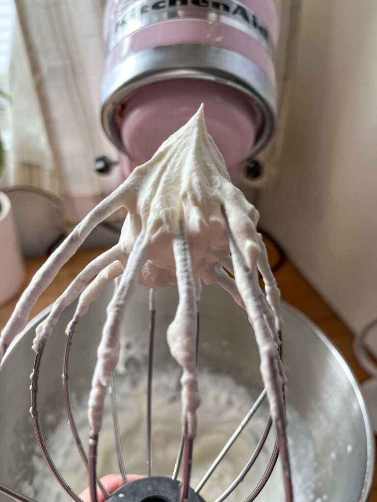 Whipping cream that has been beaten to stiff peaks on a wire whisk attachment.