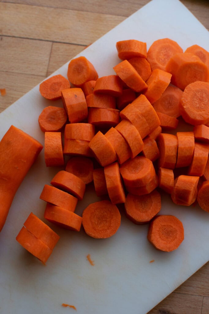 Fresh carrots cut into half inch pieces on a cutting board.