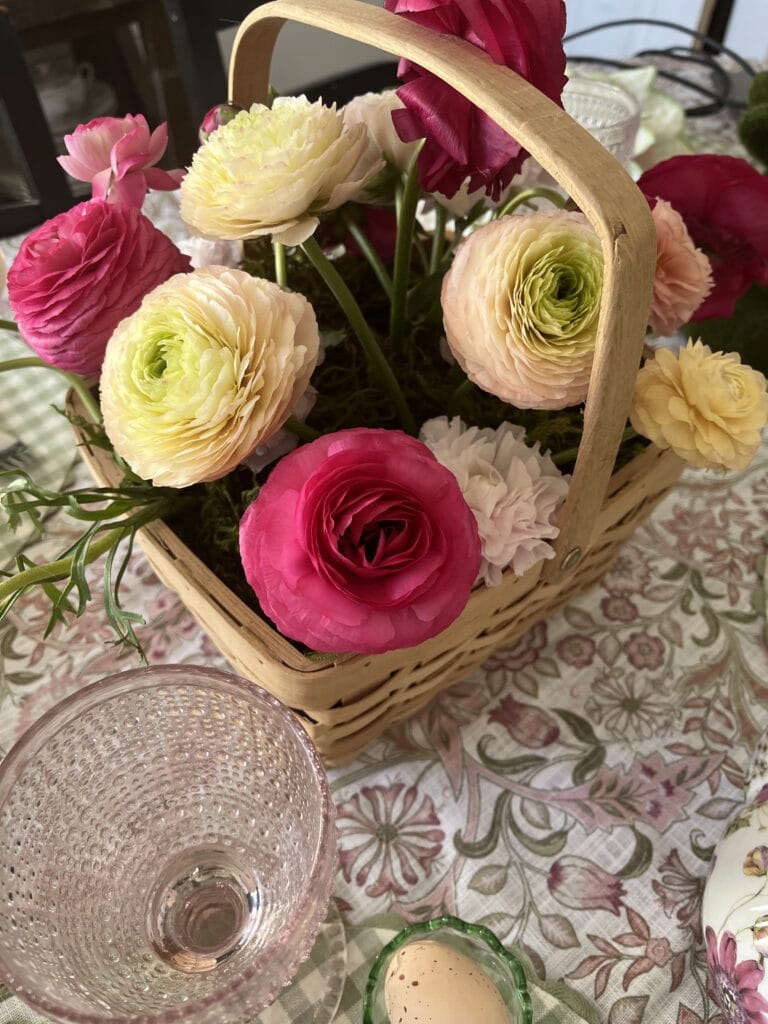 A small wicker basket fill with pink ranunculus flowers.