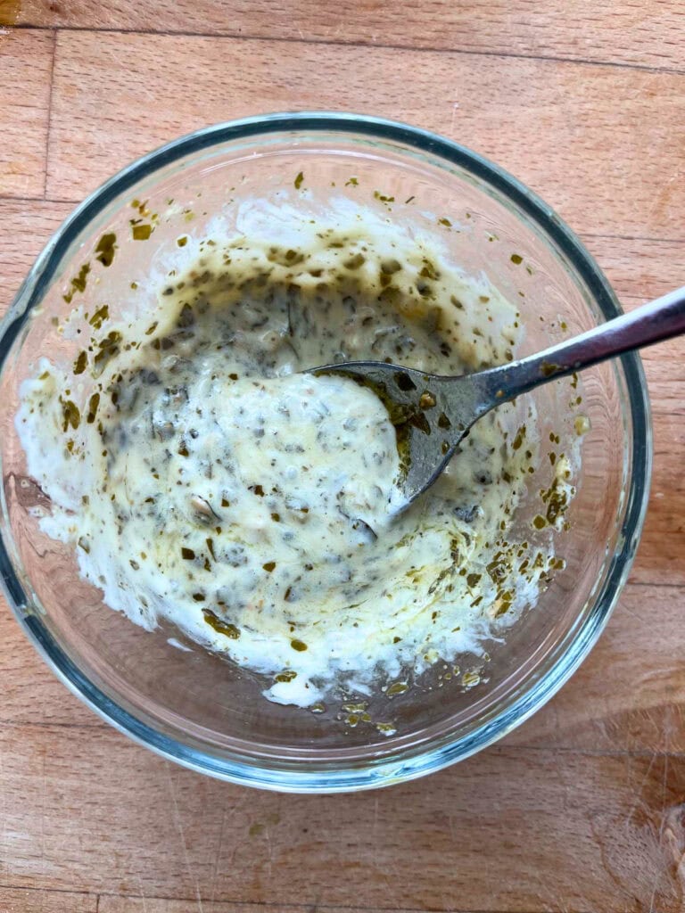 Pesto blended with mayonnaise in a small glass bowl.