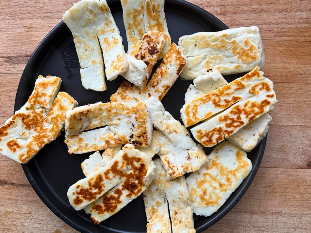 Sliced halloumi cheese that has been grilled in a hot pan until browned and crispy on the outside.