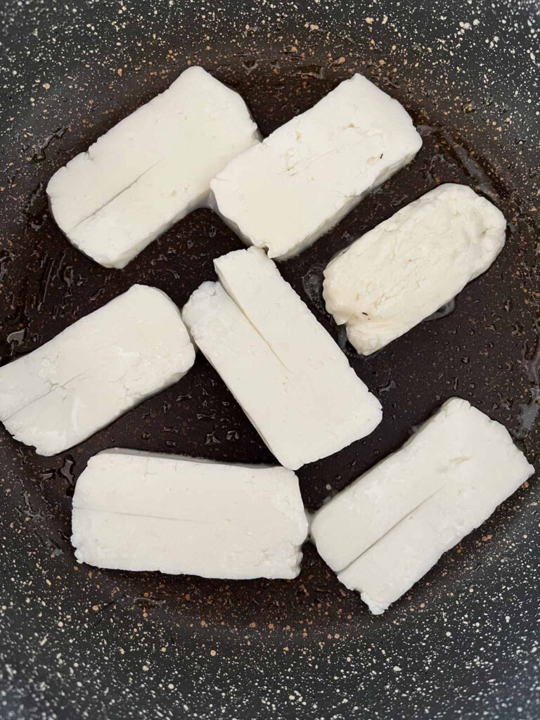 Freshly sliced halloumi cheese added to a warm pan to grill.