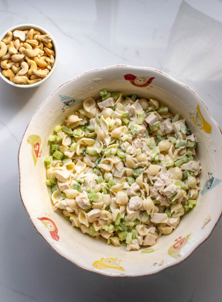 All the ingredients to make cashew chicken pasta salad stirred together ij a large serving bowl before adding the cashews.