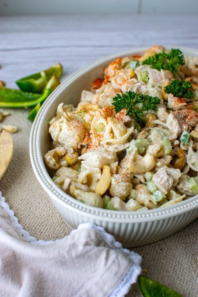 A large serving bowl filled with cashew chicken pasta salad.